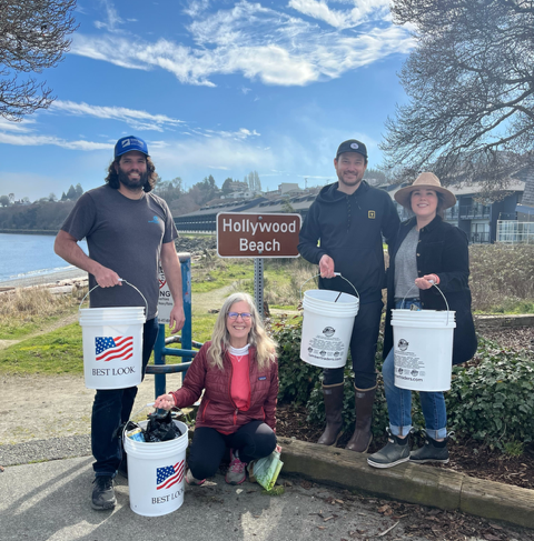 4 volunteers pose wit buckets in front of the Hollywood Beach sign