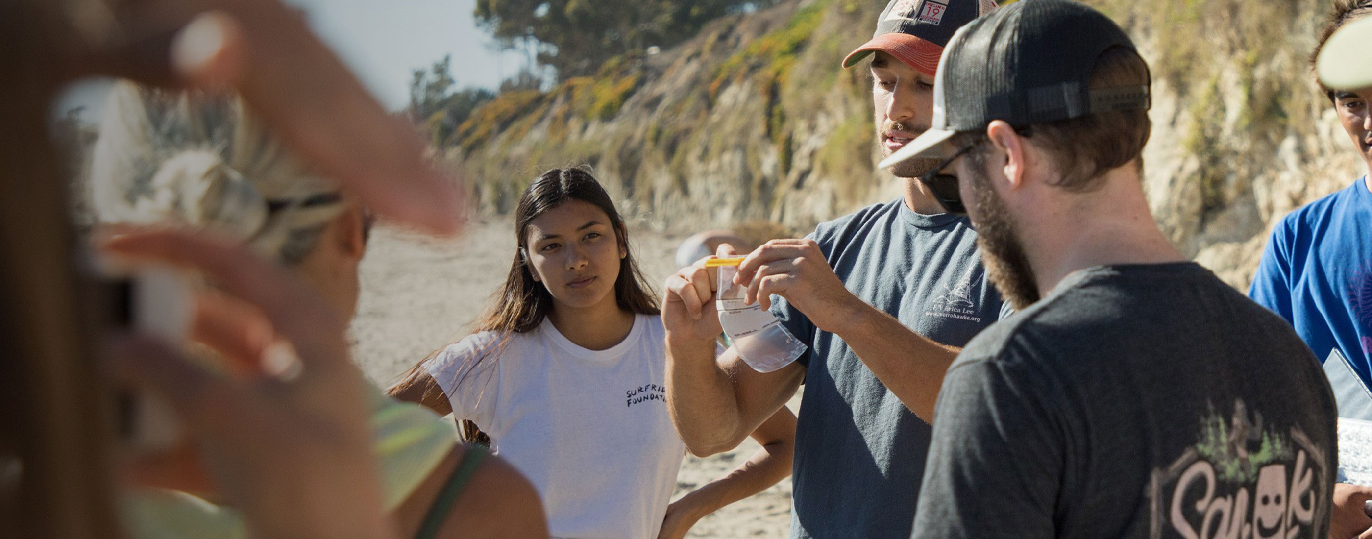 Volunteer holds up water sample bag to show other volunteers